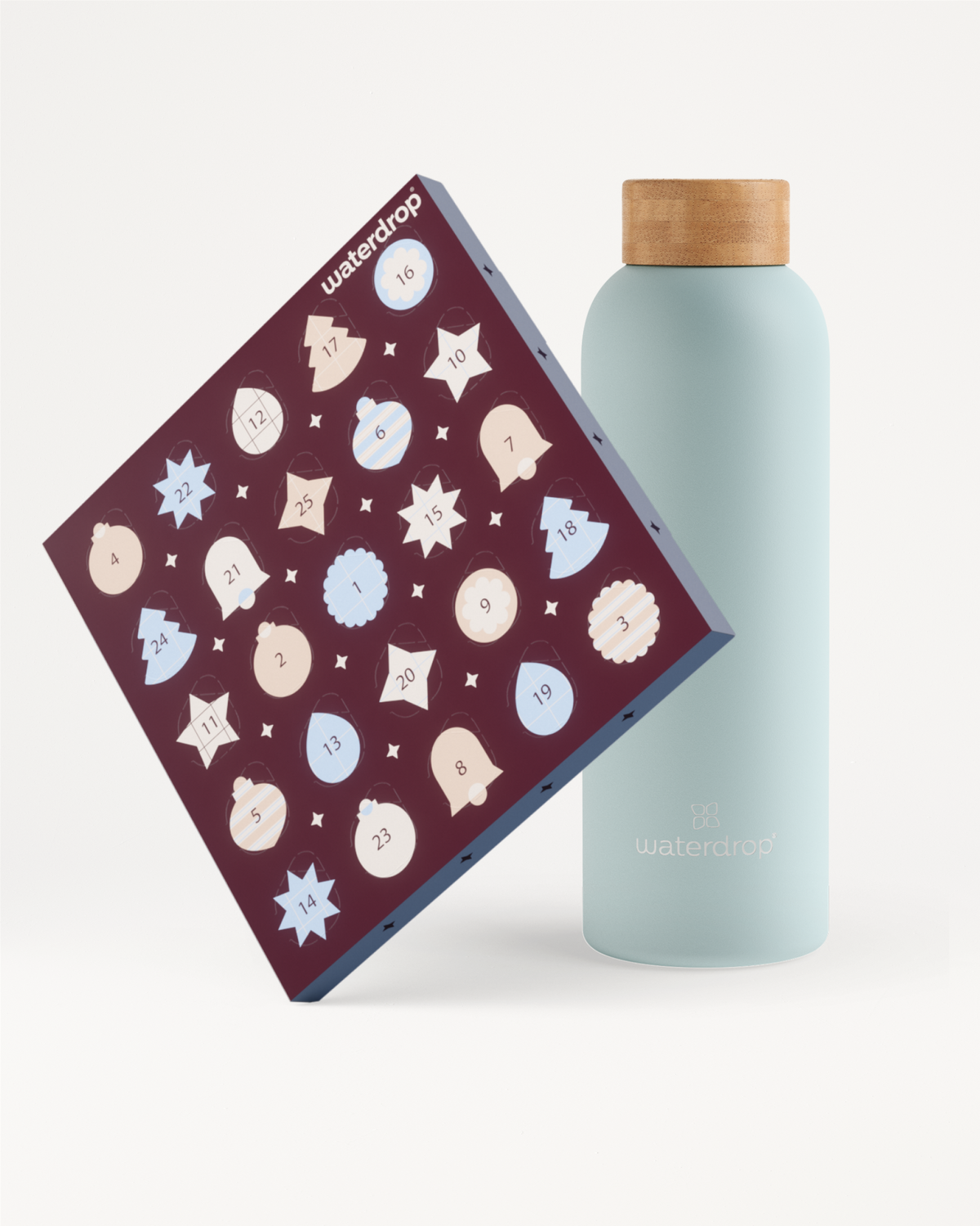Hellblaue, wiederverwendbare Flasche mit Holzdeckel neben einem violetten Adventskalender mit weißen und hellblauen Schneeflocken.