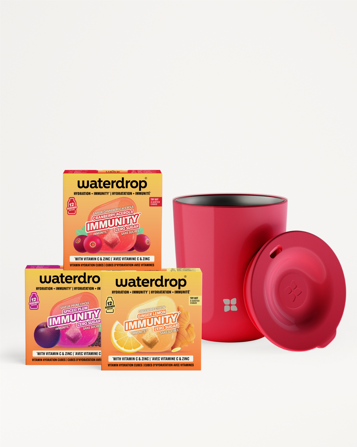 Drei bunte Boxen mit Vitaminbeuteln stehen neben einer roten zylindrischen Flasche mit rotem Deckel.