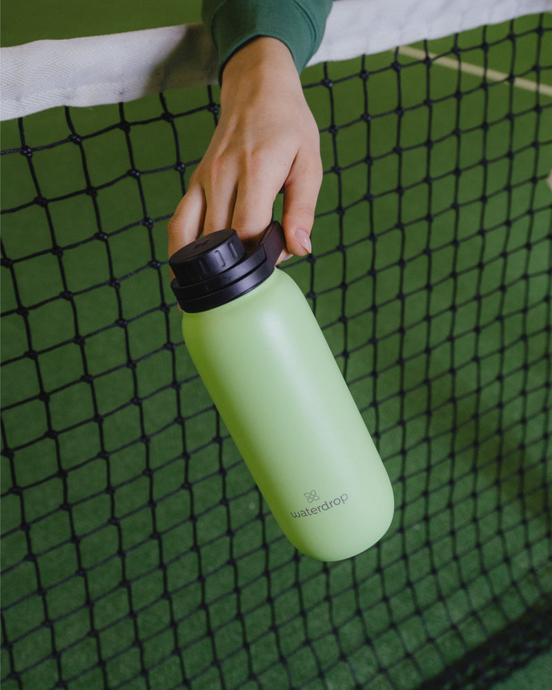 All-Purpose Thermo · Swing Lid Flasche in Hand über Tennisnetz.
