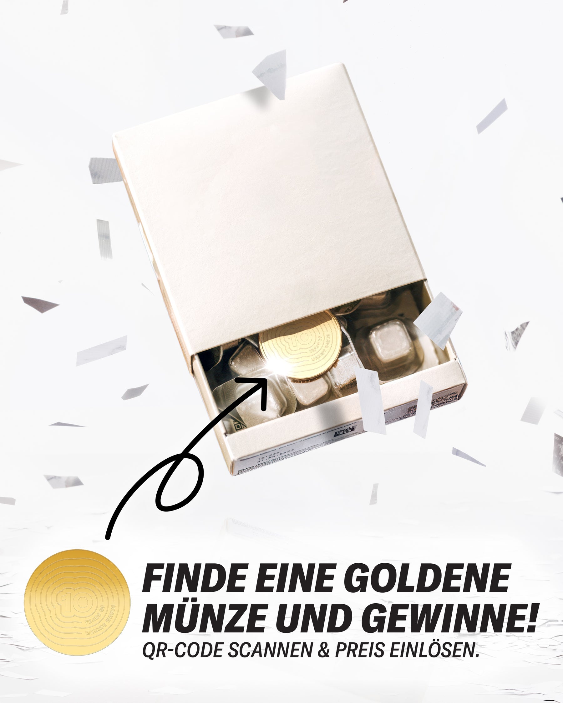 Offene weiße Geschenkbox mit Goldmünze und weiteren Münzen, umgeben von Konfetti.
