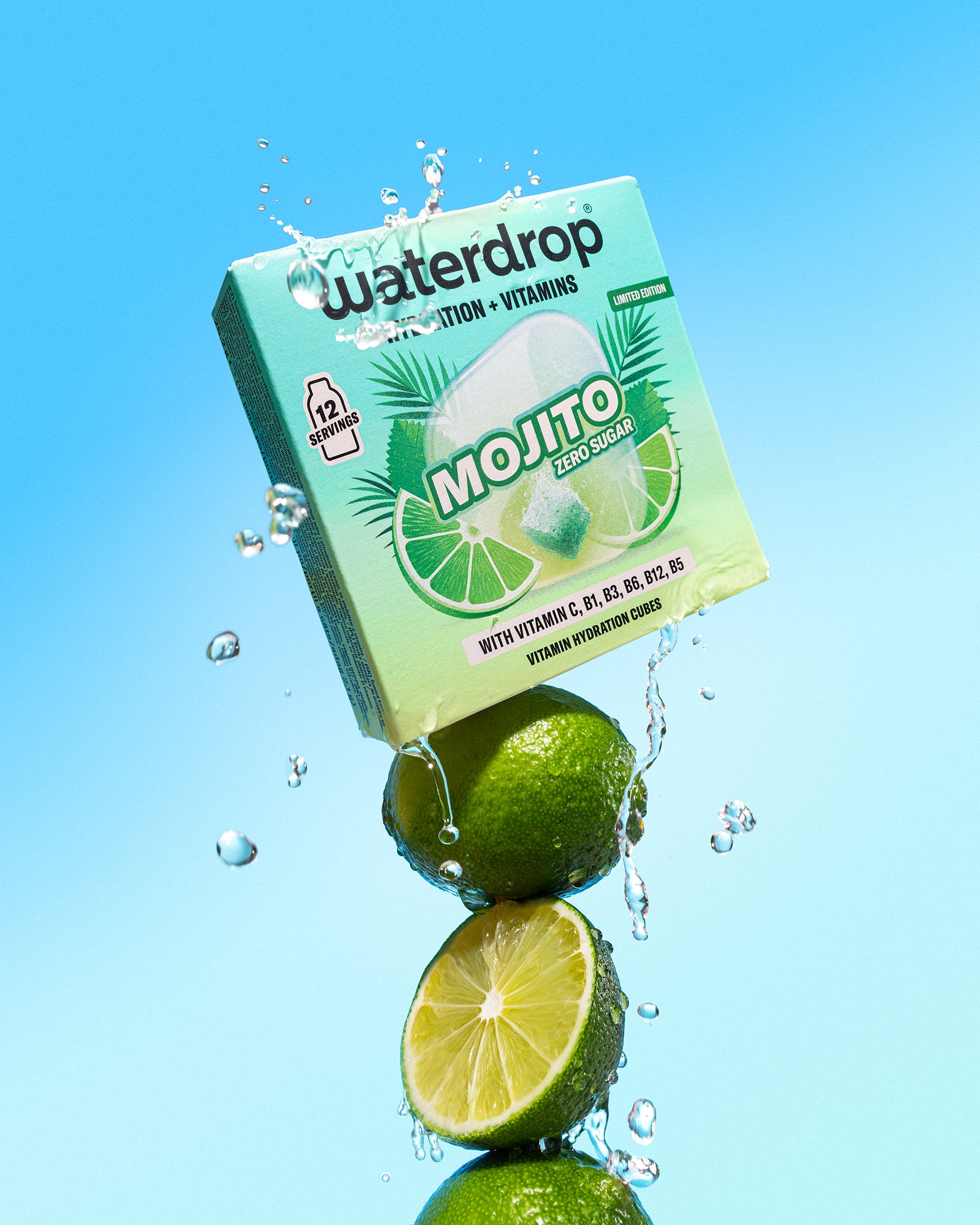 Limetten unter einer mintgrünen Getränkekiste gestapelt, Wasserspritzer vor blauem Hintergrund.
