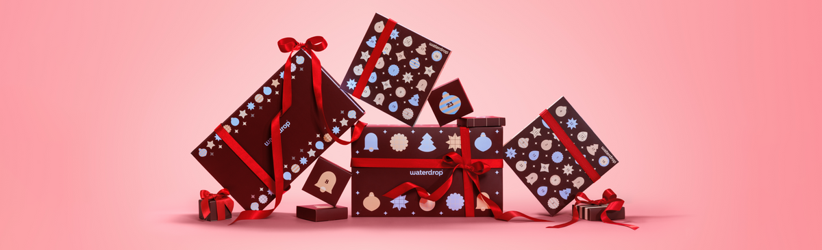 Bunte Geschenkboxen sind festlich auf einem rosa Farbverlauf arrangiert.