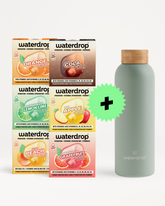 Verschiedene Waterdrop-Getränkekartons stapeln sich neben einer hellgrünen wiederverwendbaren Flasche mit Korken und einem grünen Pluszeichen.