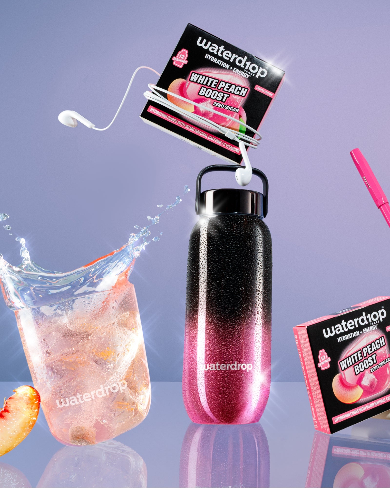 Wiederverwendbare Flasche mit pink-schwarzem Farbverlauf und Schnappgriff, angebrachte Geschmackspakete, Glas mit Eis und Pfirsichscheibe sowie pinker Strohhalm.