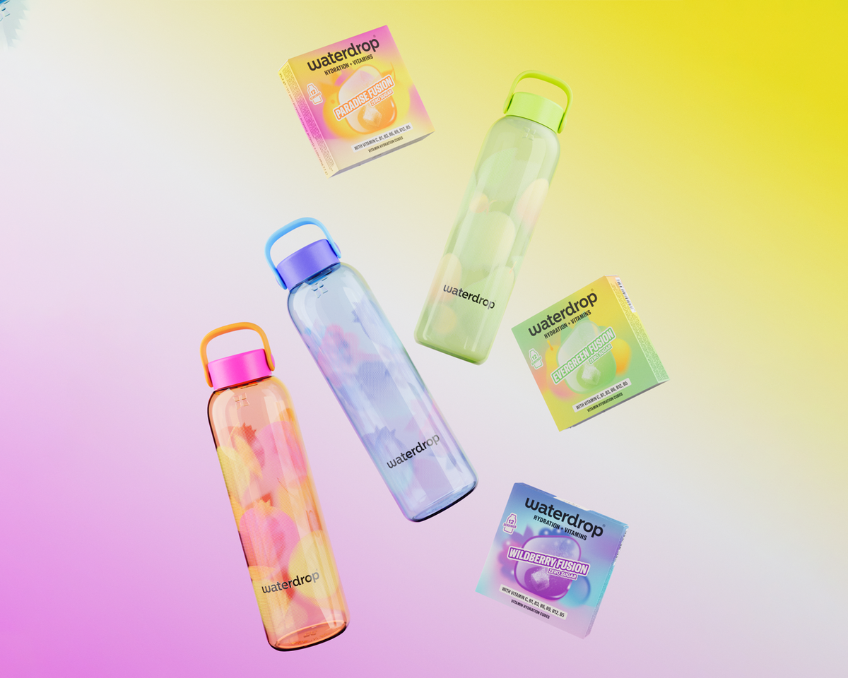 Vier transparente wiederverwendbare Wasserflaschen mit bunten Deckeln auf pastellem Hintergrund, neben passenden Verpackungen.