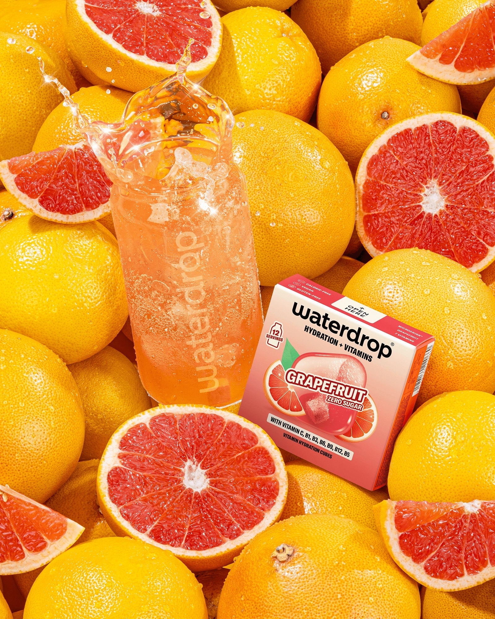 Sortiment von Grapefruits mit einer Flasche rosafarbenen Getränks und einer kleinen Box zwischen den Früchten.