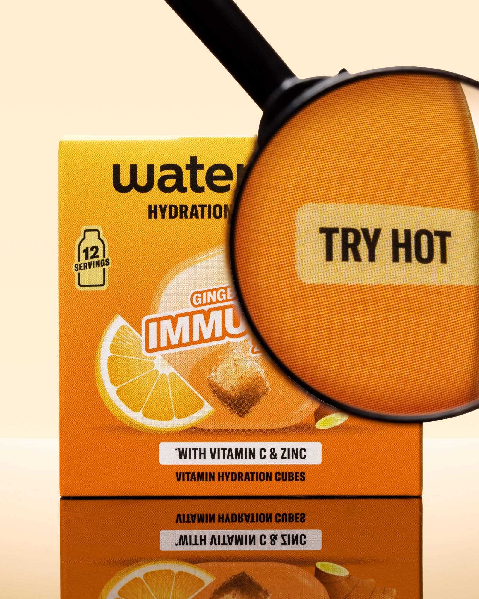 Orangene Box mit Hydratationswürfeln und Zitronenabbildung, mit Lupe über dem Paket.
