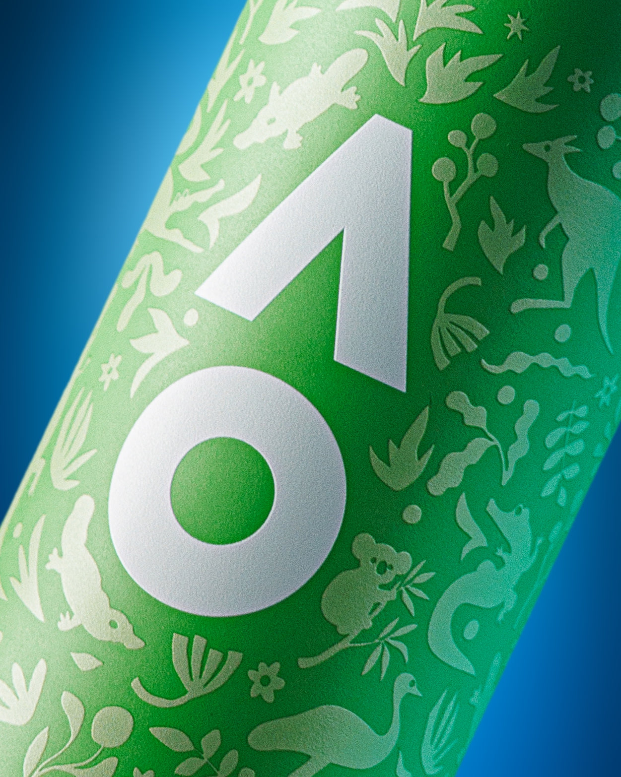 Nahaufnahme einer grünen zylindrischen Flasche mit großem weißen geometrischen Emblem und dekorativen weißen Silhouetten vor blauem Hintergrund.