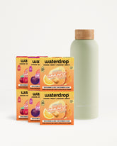 Sechs orangefarbene Getränkemischboxen neben einer hellgrünen Flasche mit Korken.