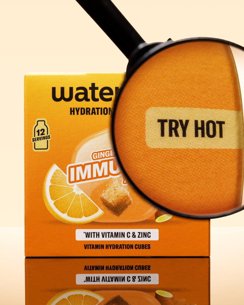 Orangefarbene Box mit Hydration-Würfeln und Vergrößerungsglas über einer orangefarbenen Würfel.