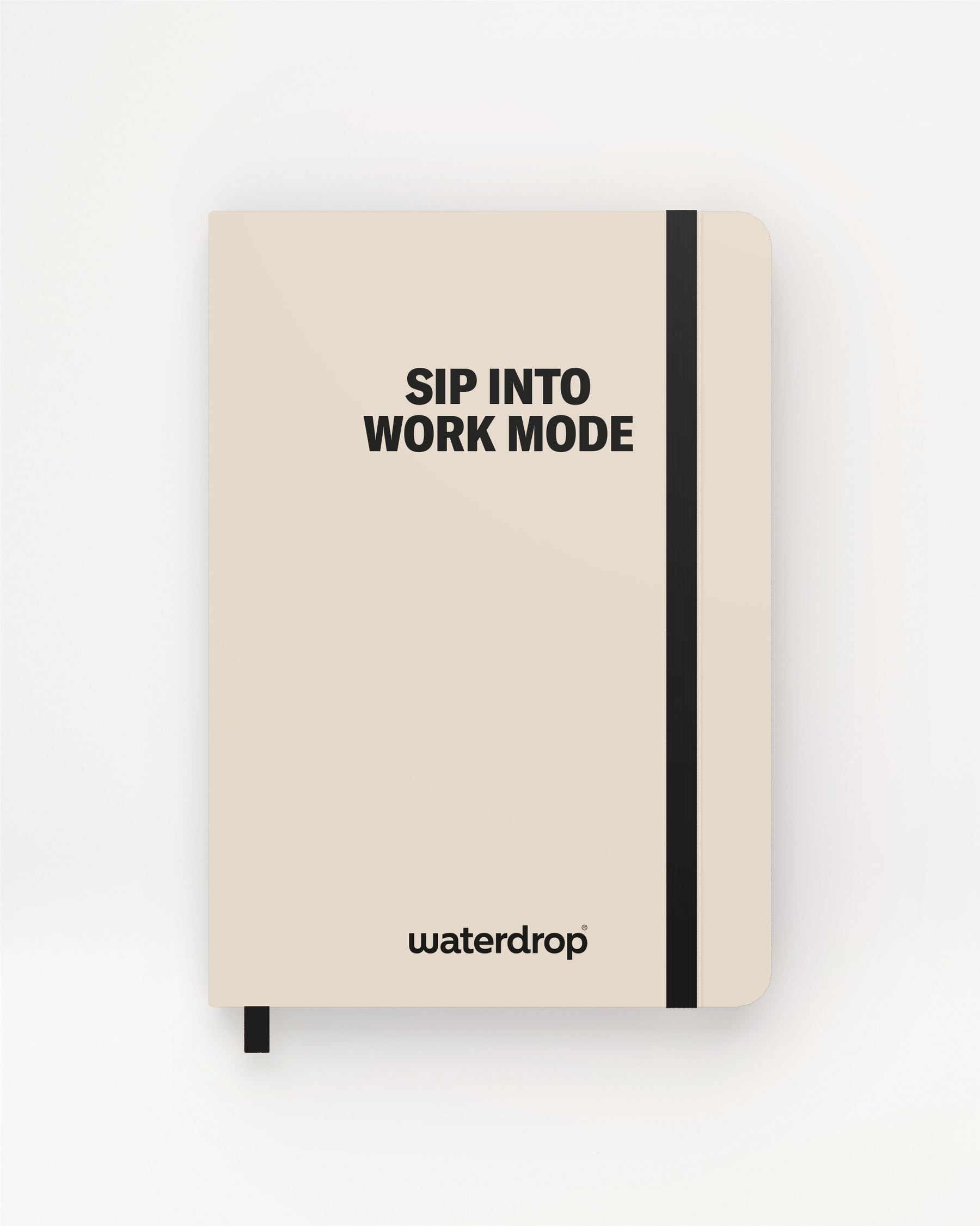 Beige Notizbuch mit schwarzem Elastikband und farblich passenden Lesebändchen vor hellem Hintergrund.