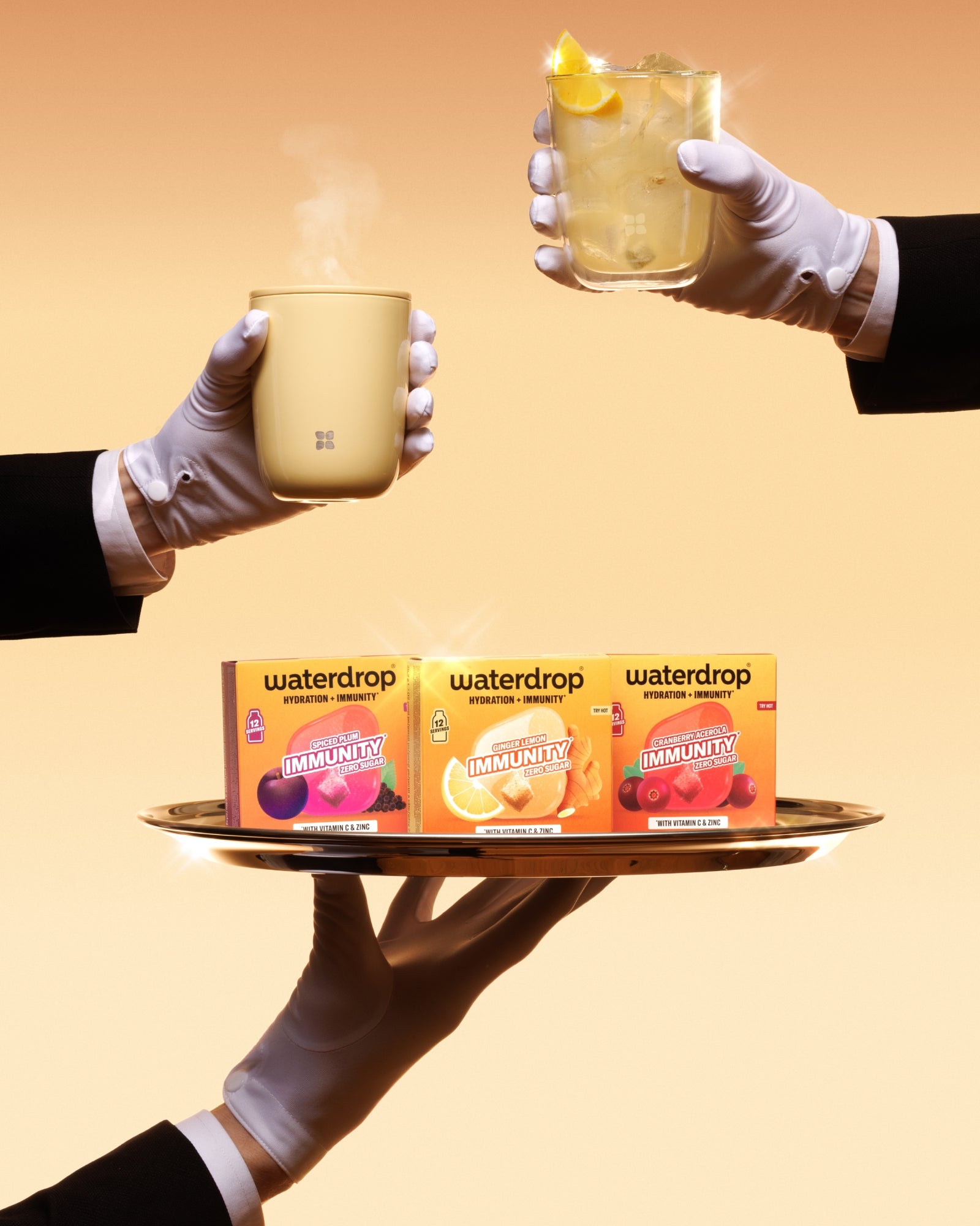 Gummierte Handschuhe halten ein Tablett mit drei Waterdrop-Verpackungen und zwei heißen Tassen vor einem warmen orangefarbenen Hintergrund.