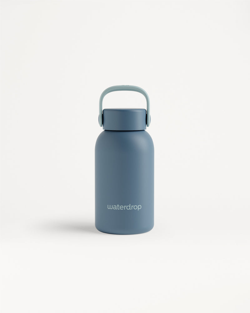 Blaue Isolierflasche mit Griff vor weißem Hintergrund.