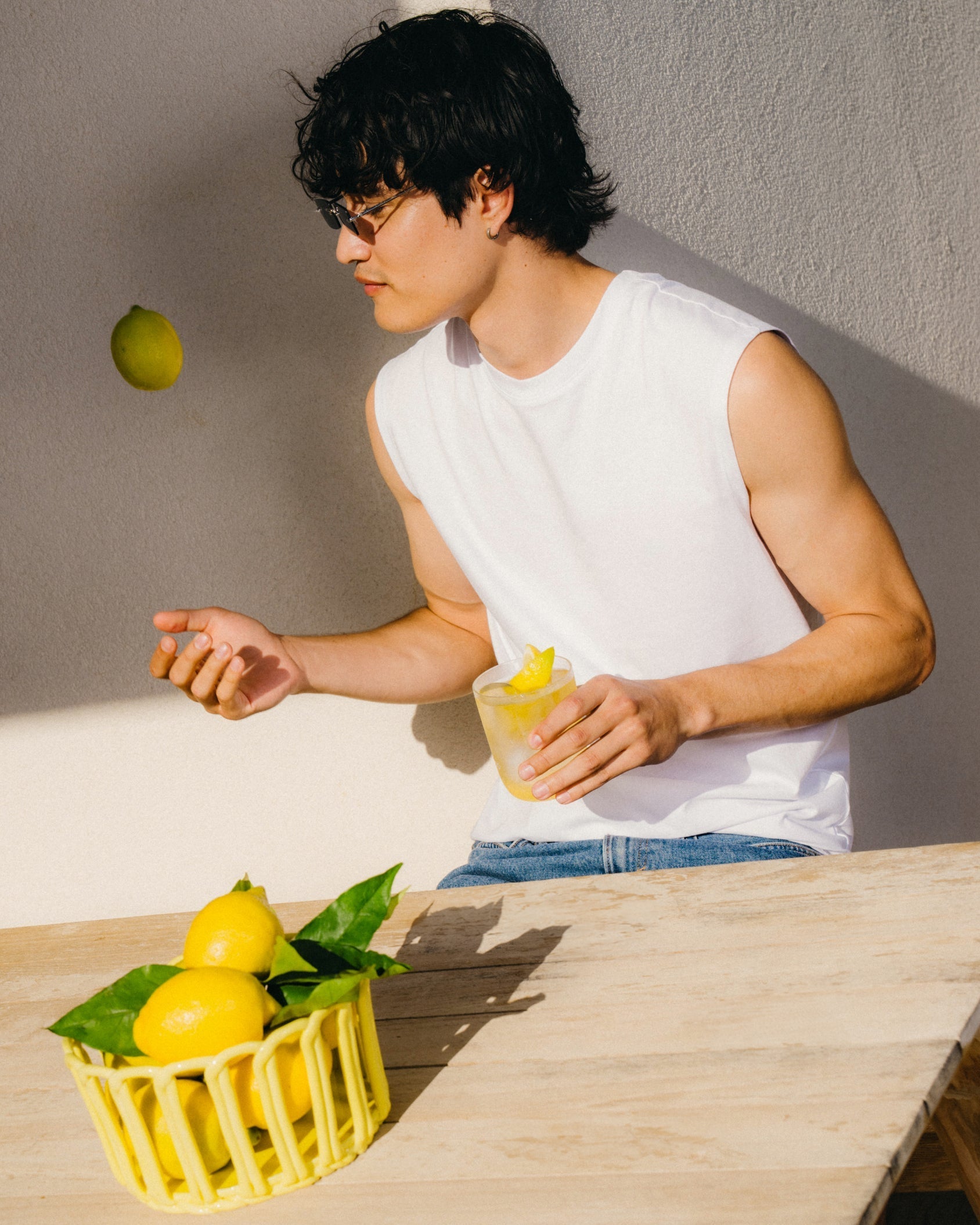 ZITRONE 3+1: Person mit Zitronengetränk und Zitronen am Tisch.